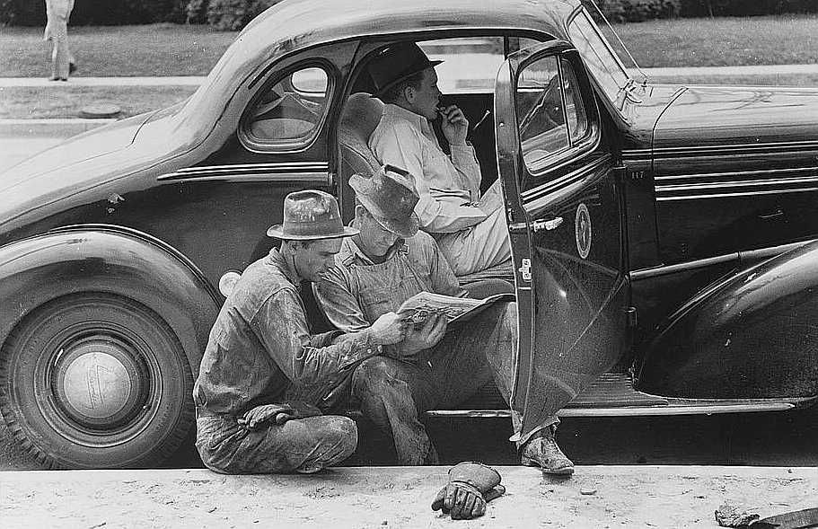 Oil field workers taking timeout to read the paper, oil well, Kilgore, Texas  Photo: Russell Lee