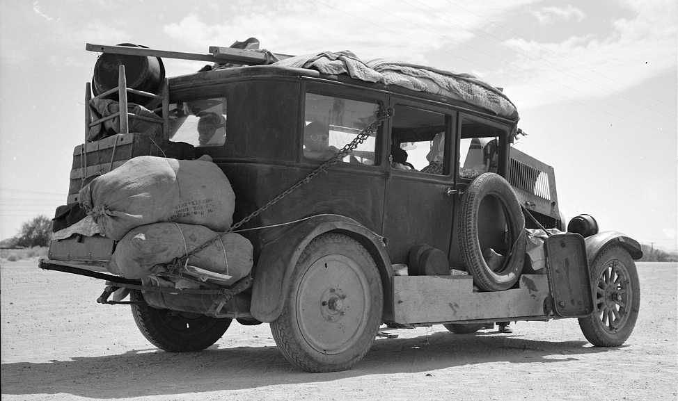 Family of nine from Fort Smith, Arkansas, trying to repair their car on road between Phoenix and Yuma, Arizona. On their way to try to find work in the California harvests   Photo: Dorothea Lange